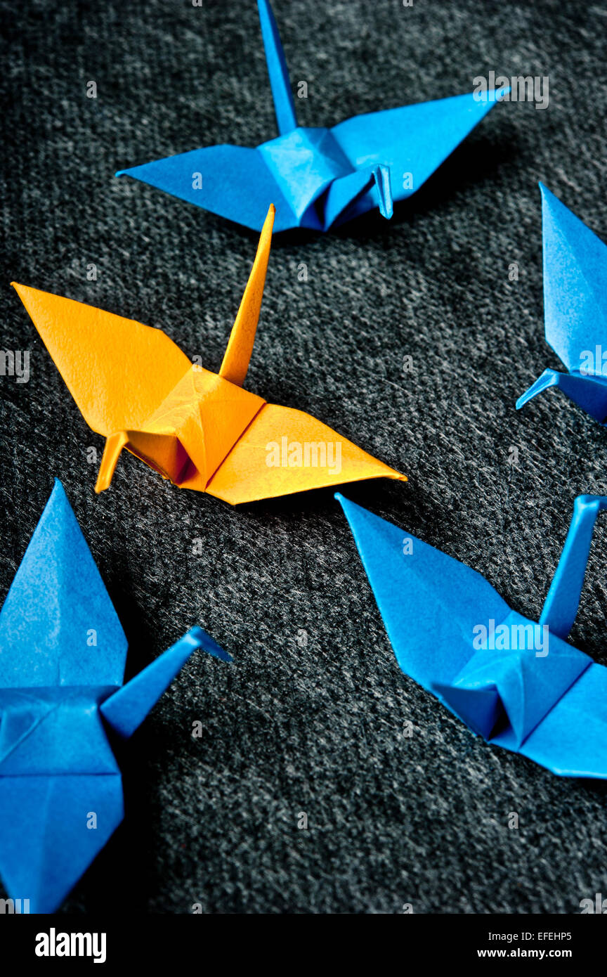 origami birds, one yellow the others blue Stock Photo