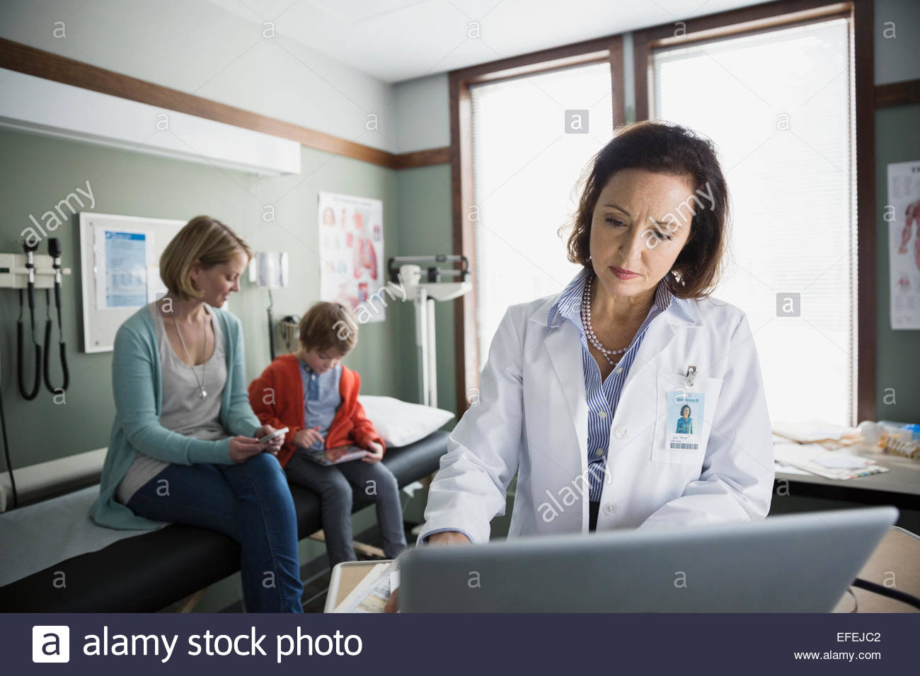 Pediatrician using laptop in examination room Stock Photo