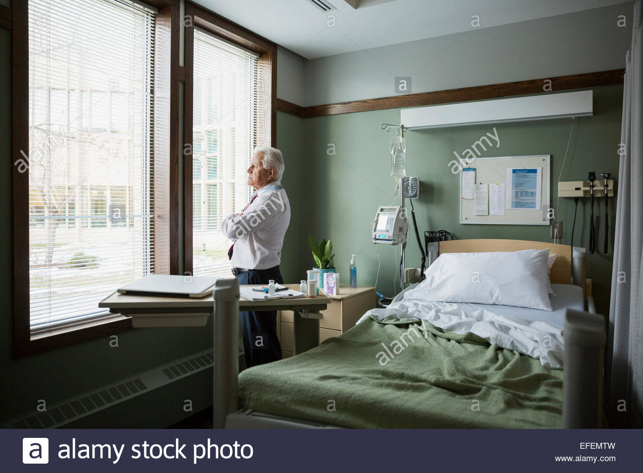 Pensive doctor looking out hospital room window Stock Photo Alamy