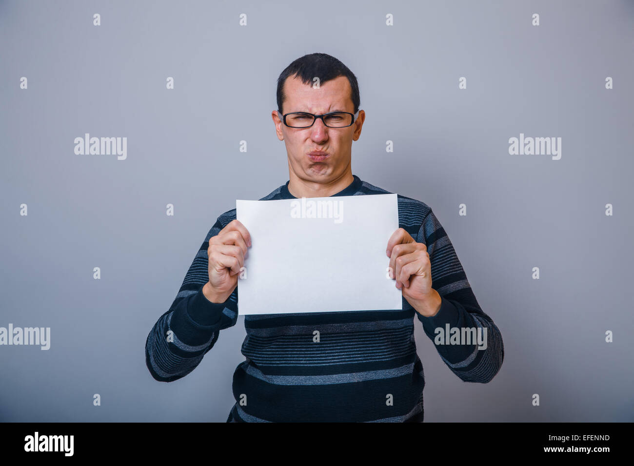 European-looking man 30 years holding a blank sheet of discon Stock Photo