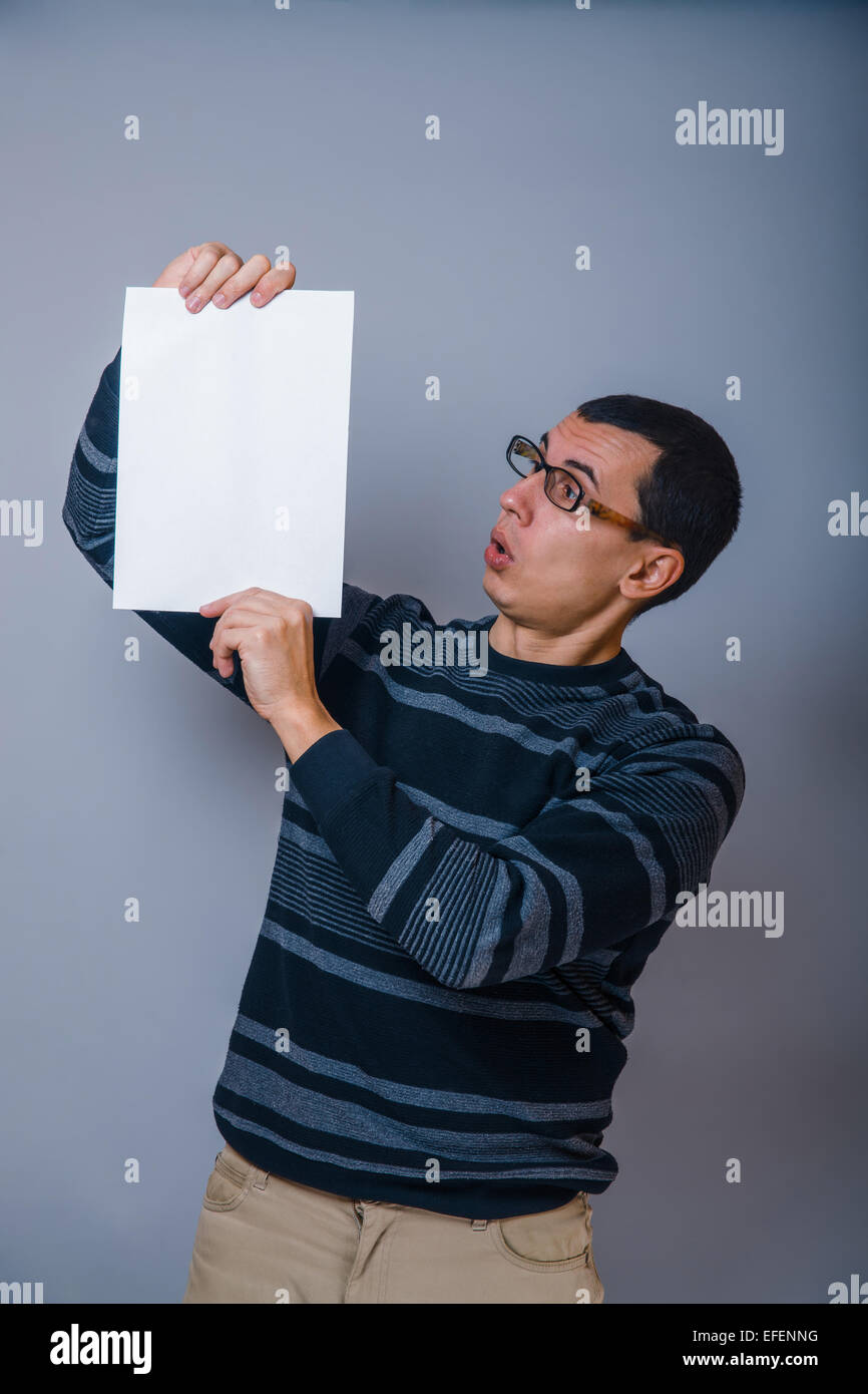 European-looking man of 30 years holding a blank sheet, surprise Stock Photo