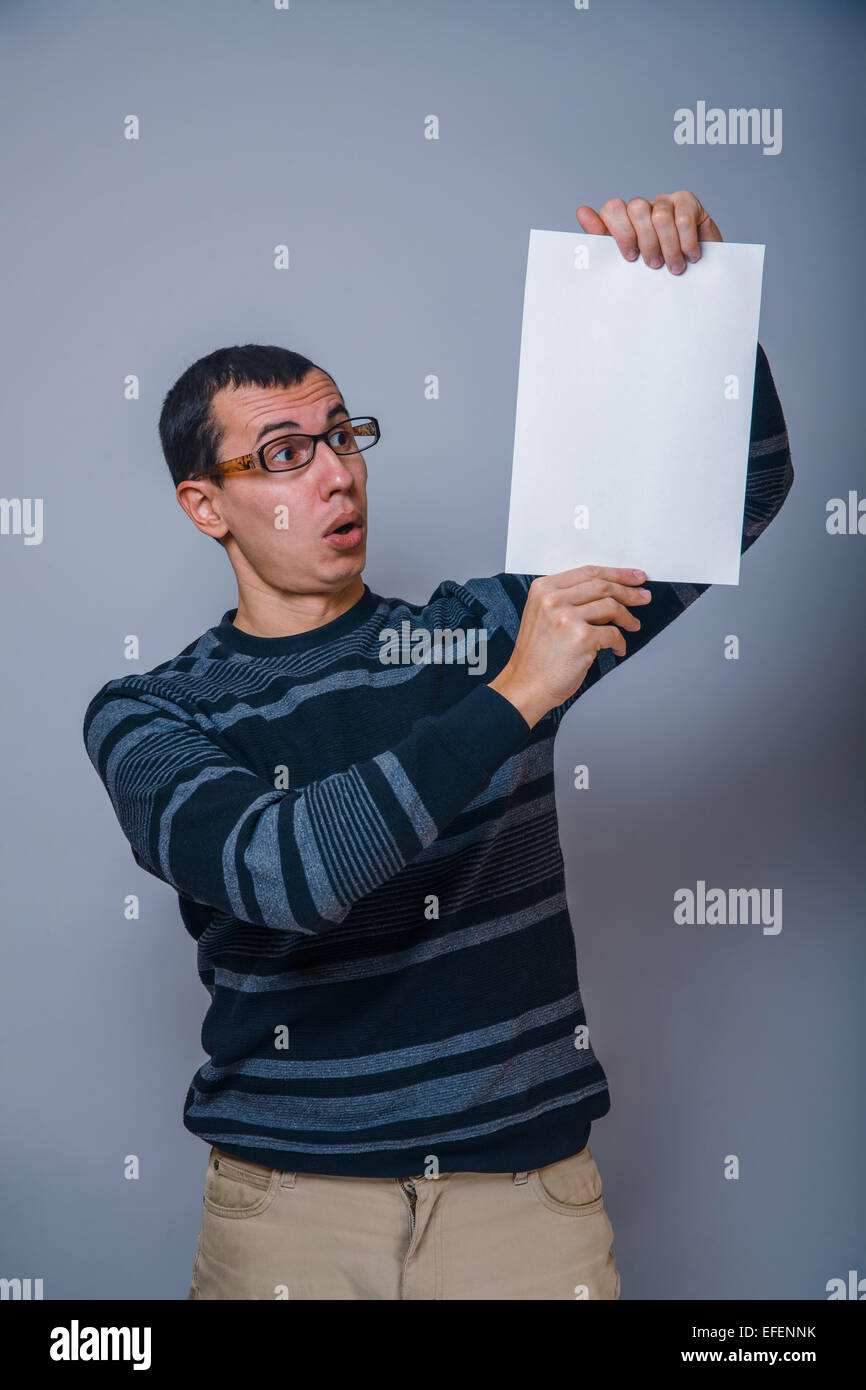 European-looking man of 30 years holding blank sheet, surprise Stock Photo