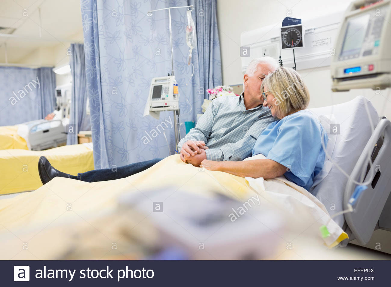 Husband comforting wife in hospital bed Stock Photo