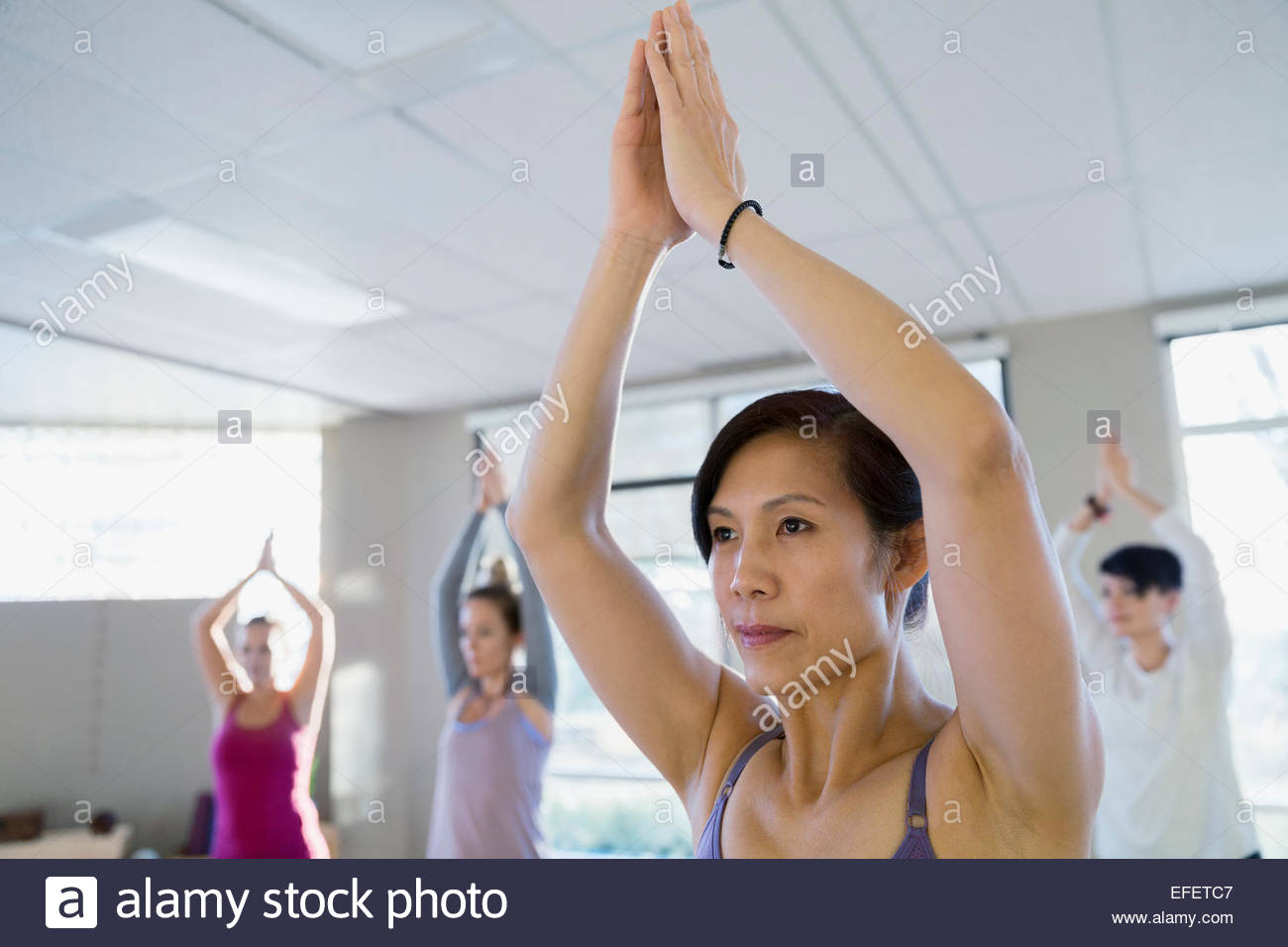Women with hands clasped overhead in yoga Stock Photo