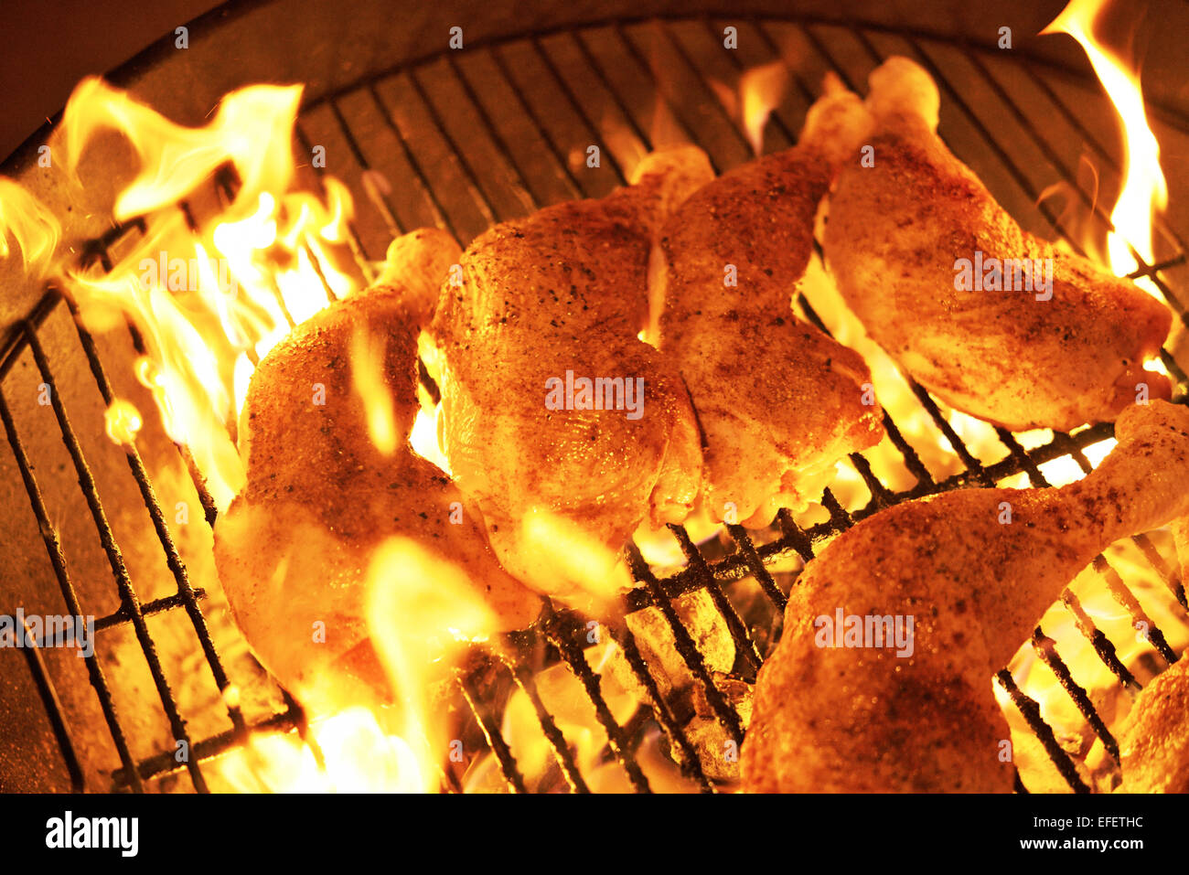Chicken on a grill with flames Stock Photo
