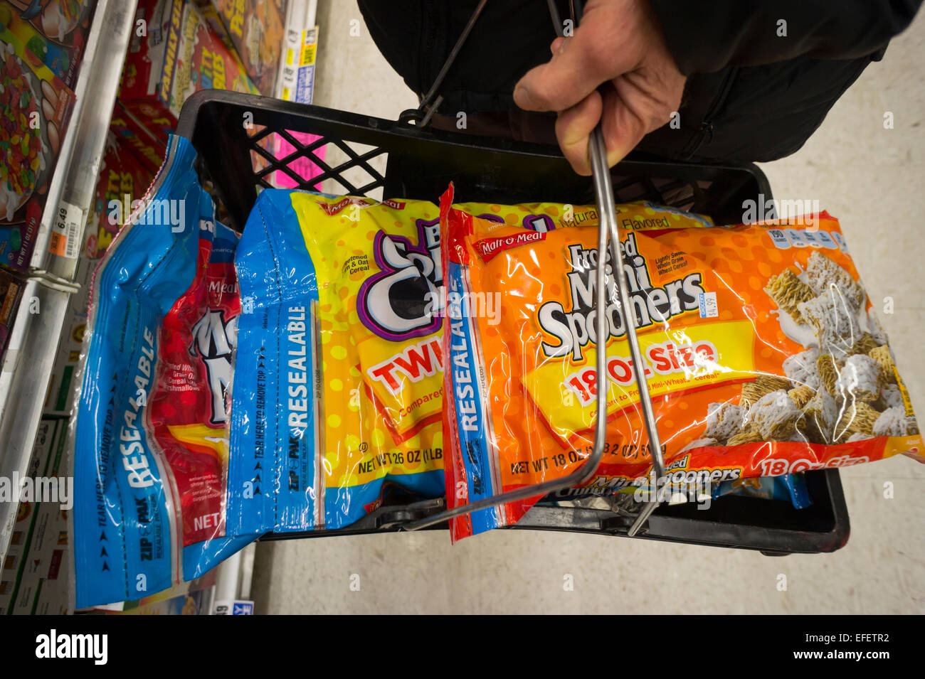 A shopper fills her basket with bags of MOM Brands (formerly Malt-O-Meal) sugary breakfast cereals in a supermarket in New York on Tuesday, January 27, 2015. Post Holdings whose brands include Grape Nuts and Raisin Bran is buying MOM Brands, manufacturer of iconic cereals such as Marshmallow Mateys and Golden Puffs in a deal worth $1.15 billion. The acquisition gives Post and 18 percent share of the breakfast cereal market after Kellogg's at 32% and General Mills at 31%. (© Richard B. Levine) Stock Photo
