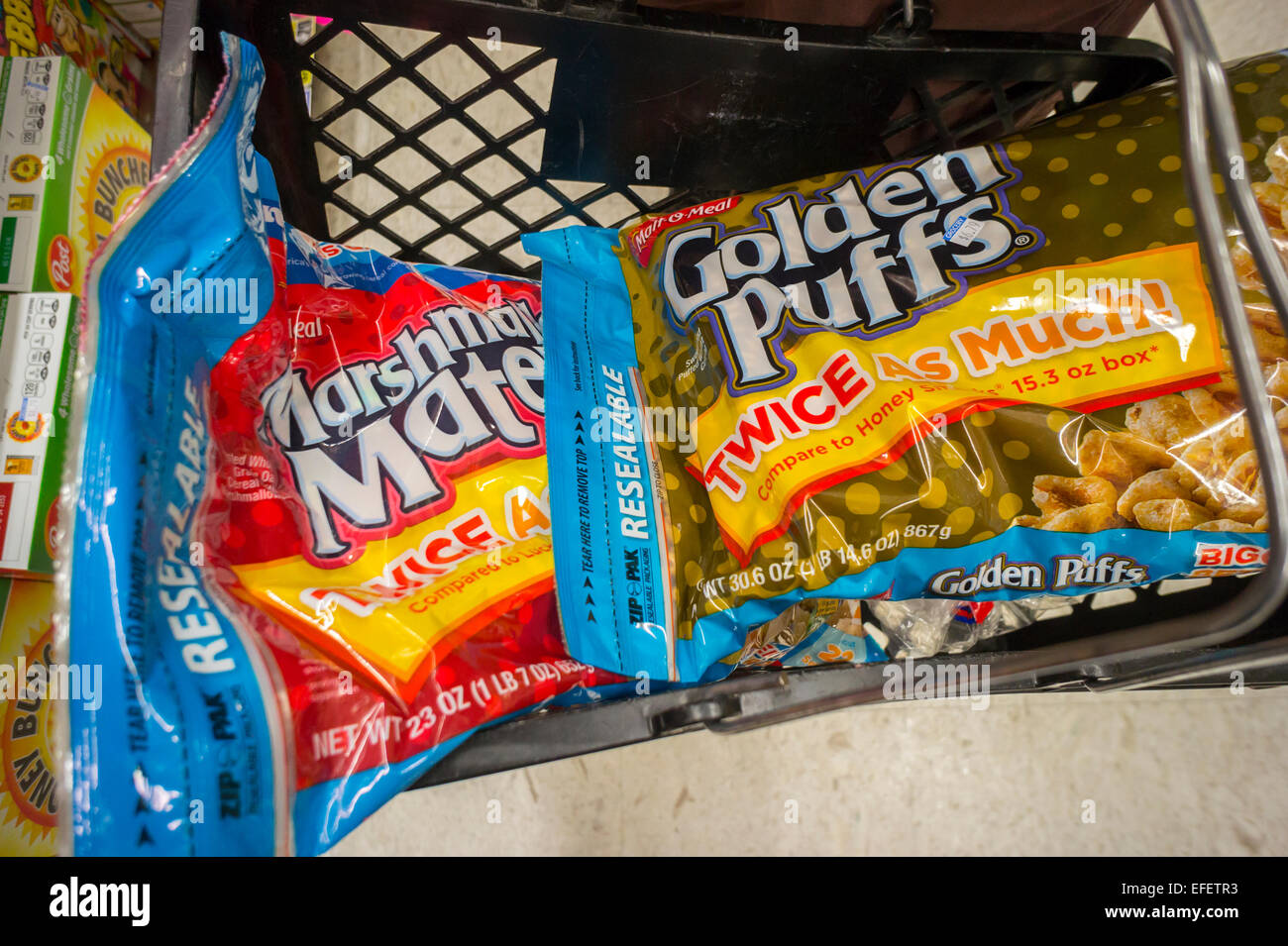 A shopper fills her basket with bags of MOM Brands (formerly Malt-O-Meal) sugary breakfast cereals in a supermarket in New York on Tuesday, January 27, 2015. Post Holdings whose brands include Grape Nuts and Raisin Bran is buying MOM Brands, manufacturer of iconic cereals such as Marshmallow Mateys and Golden Puffs in a deal worth $1.15 billion. The acquisition gives Post and 18 percent share of the breakfast cereal market after Kellogg's at 32% and General Mills at 31%. (© Richard B. Levine) Stock Photo