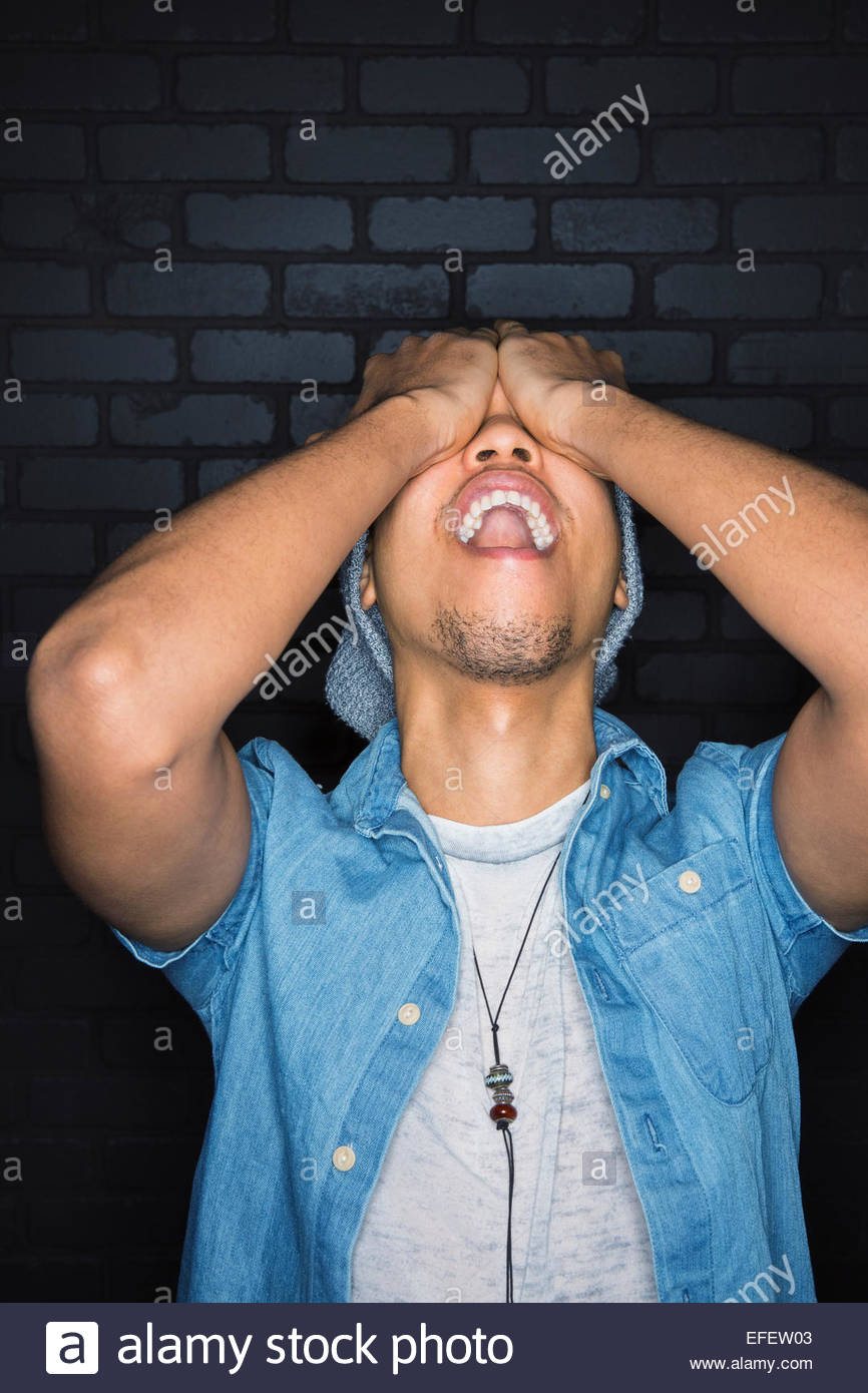 Portrait of laughing man covering eyes Stock Photo Alamy