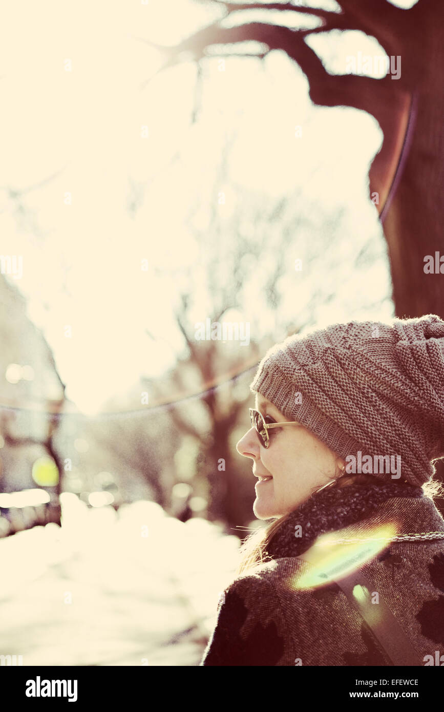 A women in a hat walking down the street with a sun glare during the winter Stock Photo