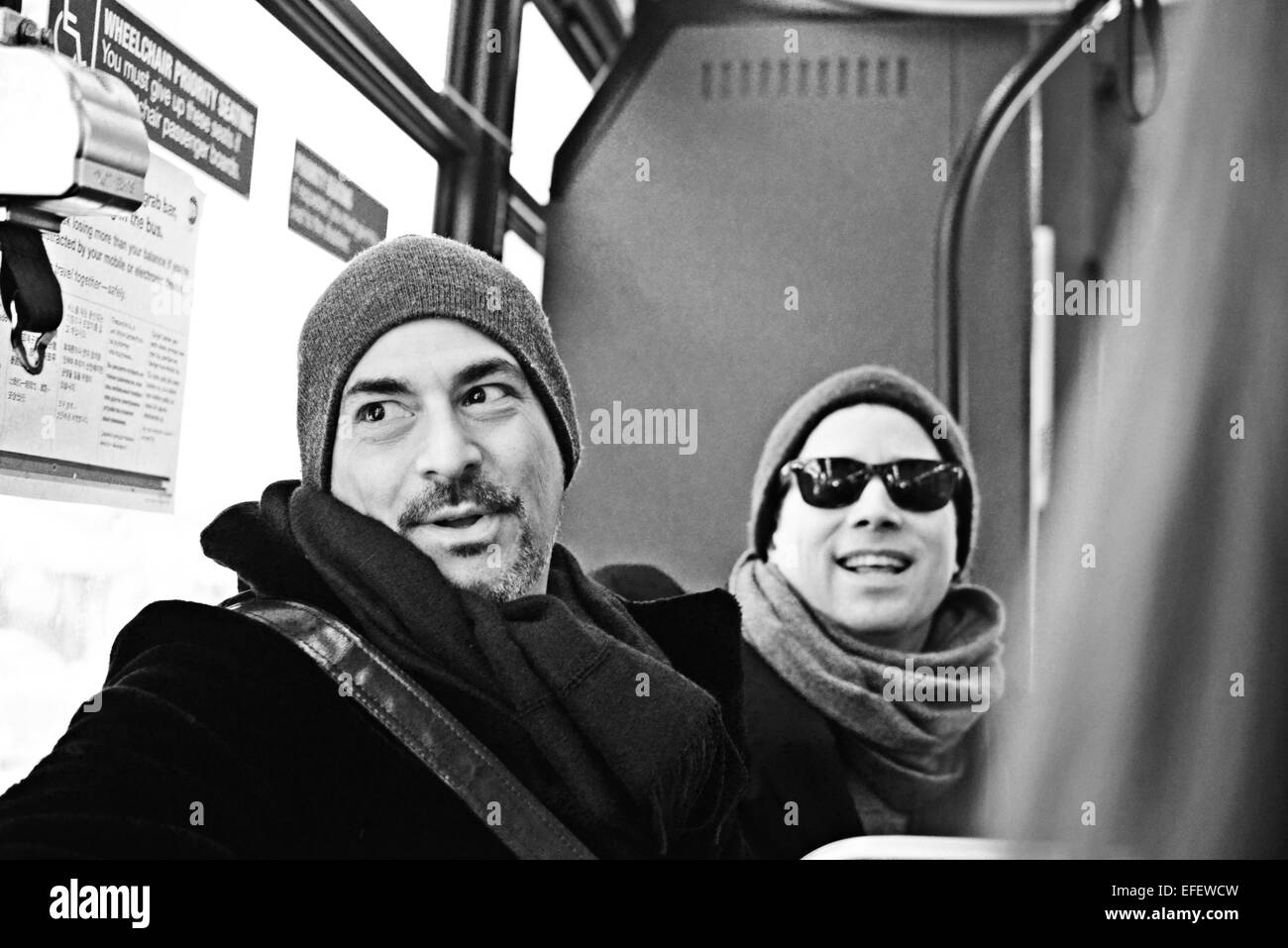 Two men sitting on bus laughing and talking in BW Stock Photo