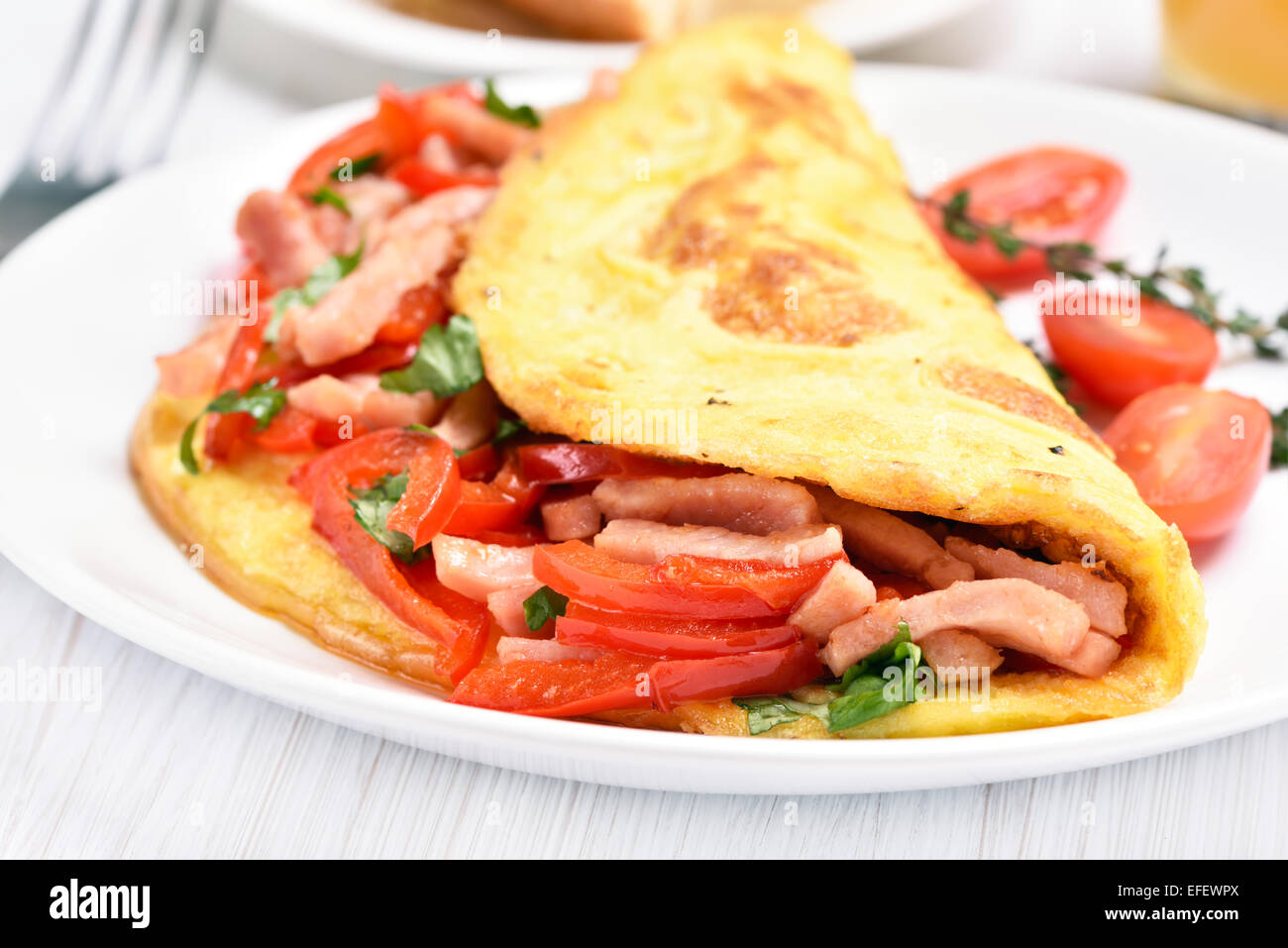 Omelette with vegetables and ham on white plate, close up view Stock Photo