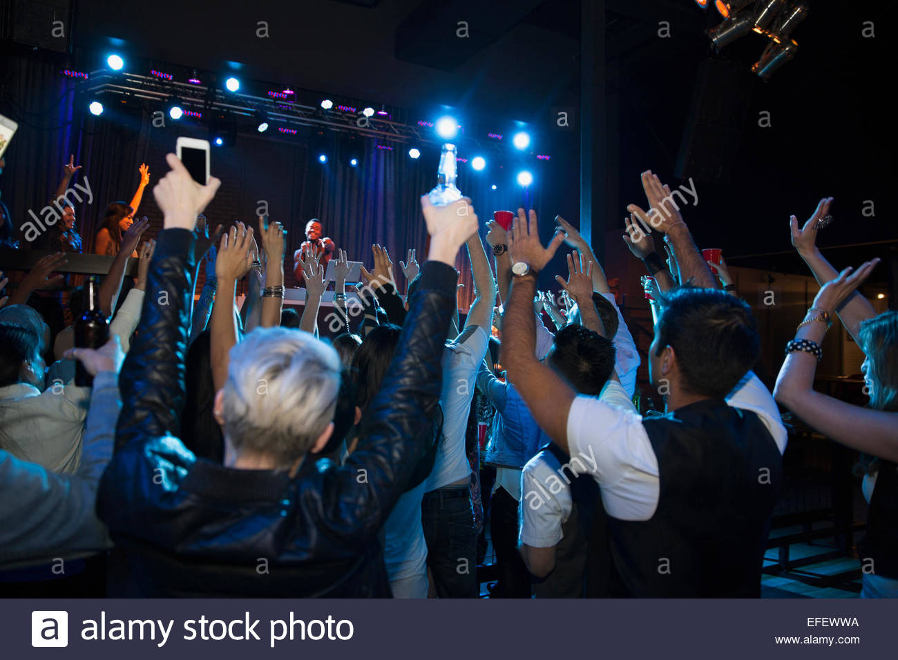 Crowd cheering for DJ on stage at nightclub Stock Photo