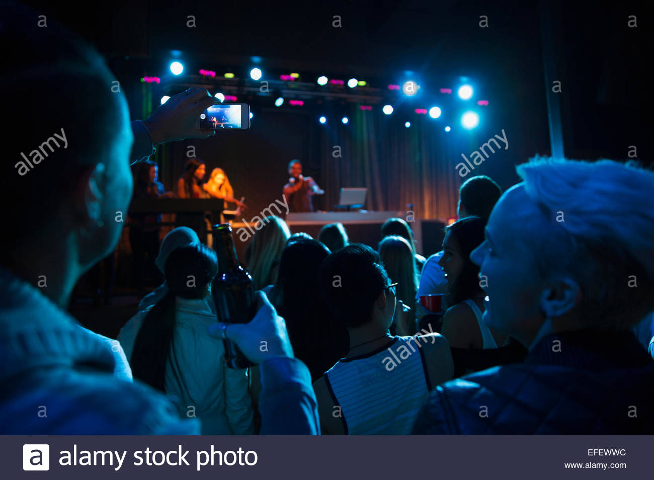 Crowd watching DJ on stage in nightclub Stock Photo