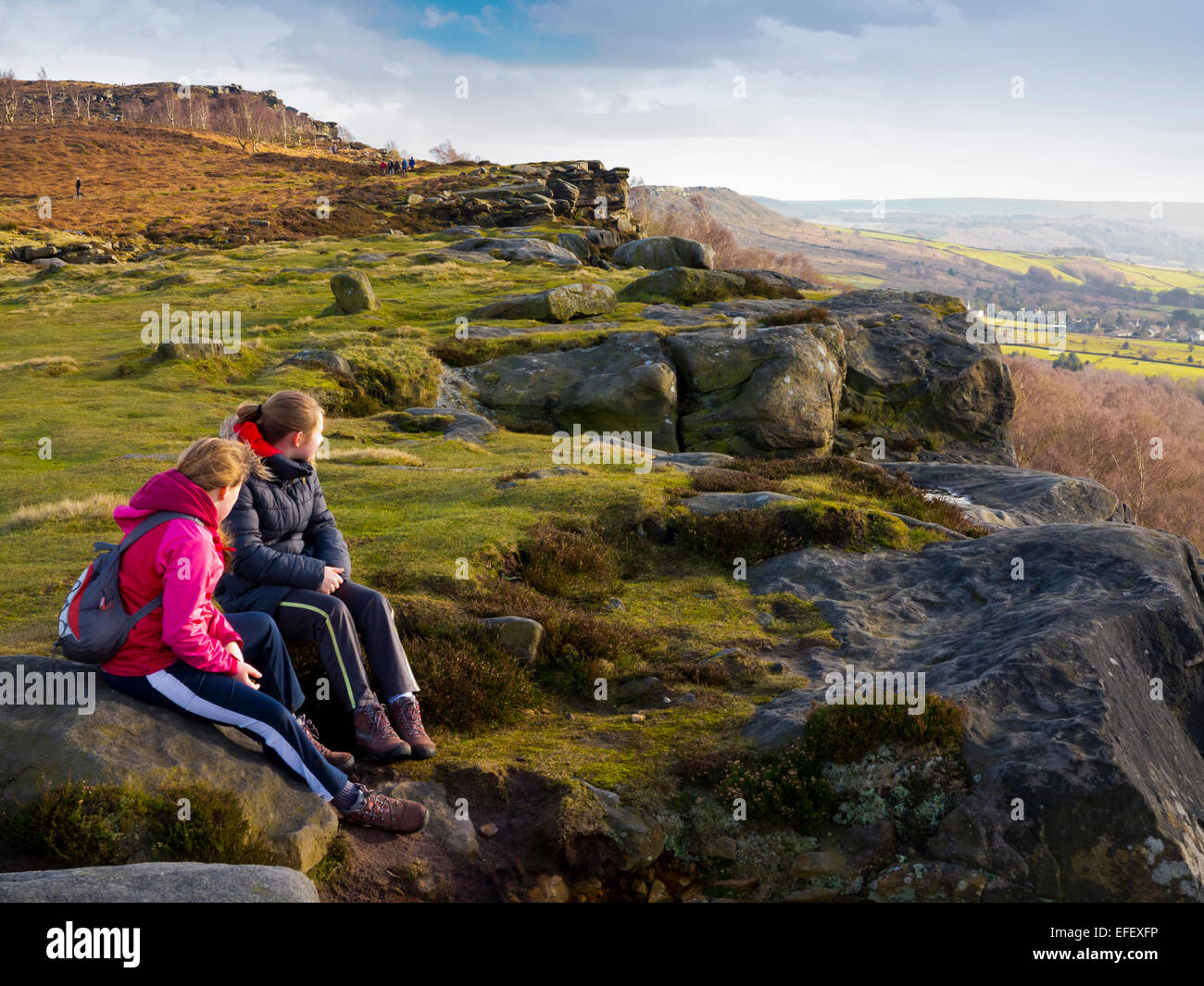 Two girls sitting on rocks enjoying the view from Froggatt Edge in the ...