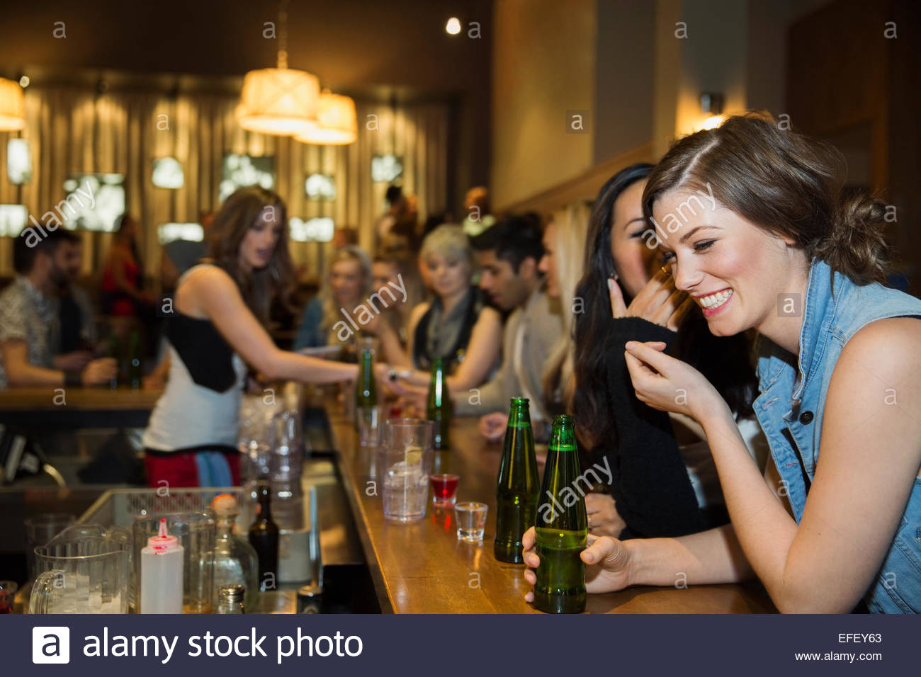Women laughing and drinking at bar Stock Photo