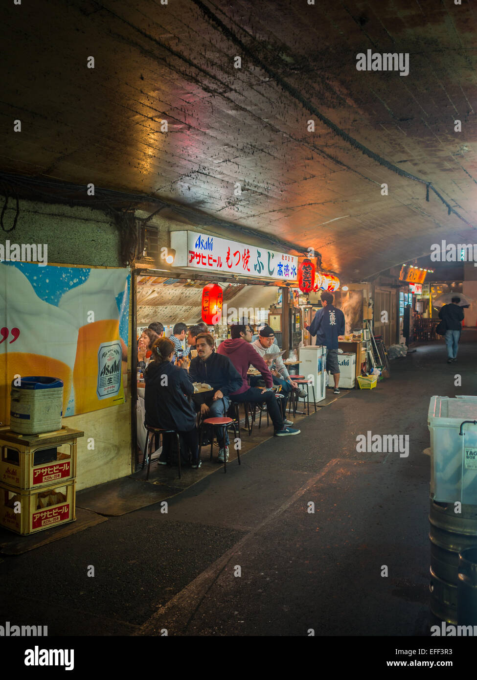 People eating in a street food place under the train tracks in central Tokyo Stock Photo