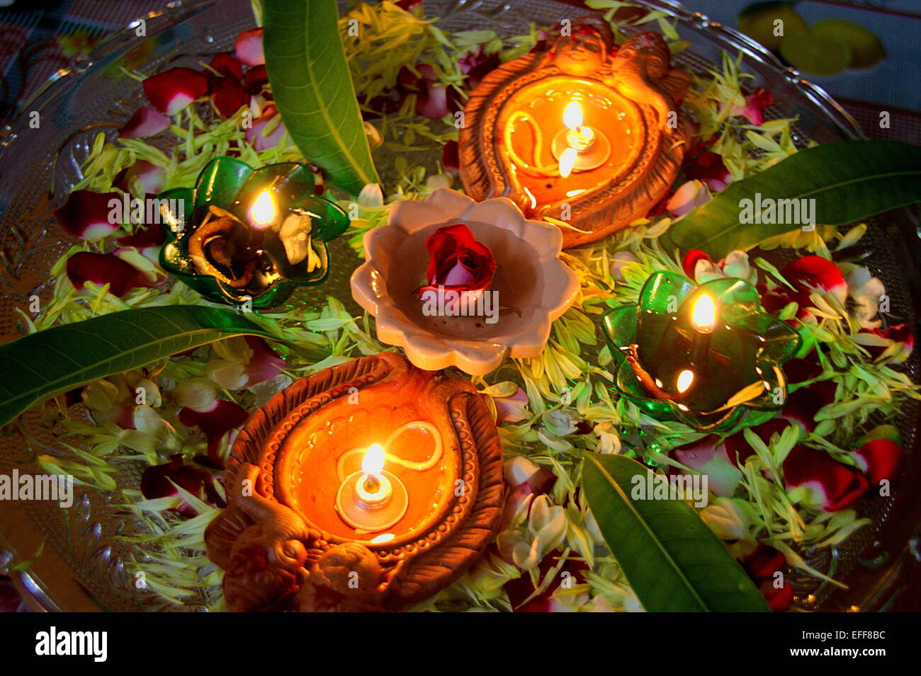 Lighted red earth oil lamps decked with flower petals during festival of Deepavali in India, Asia Stock Photo