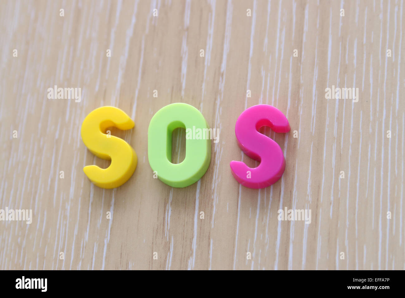 SOS spelled using Magnetic Uppercase Letters Stock Photo