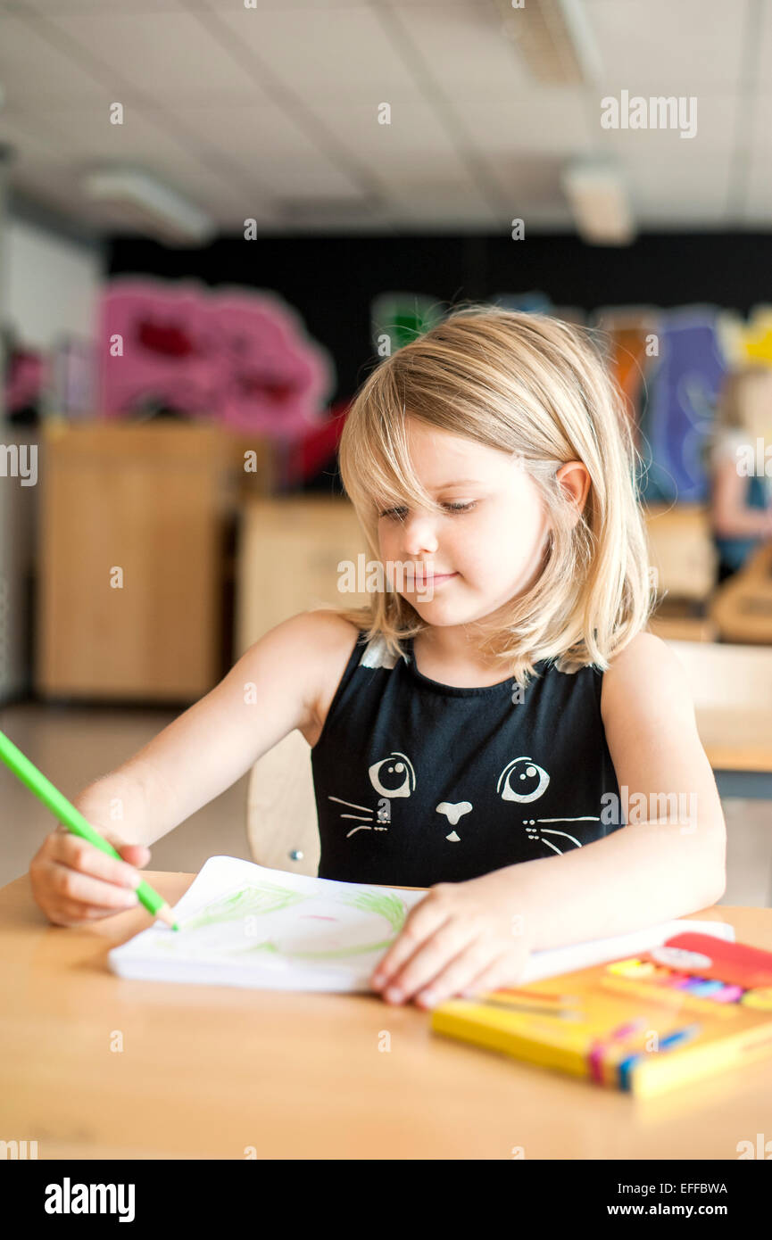 Cute girl drawing with color pencil in classroom Stock Photo