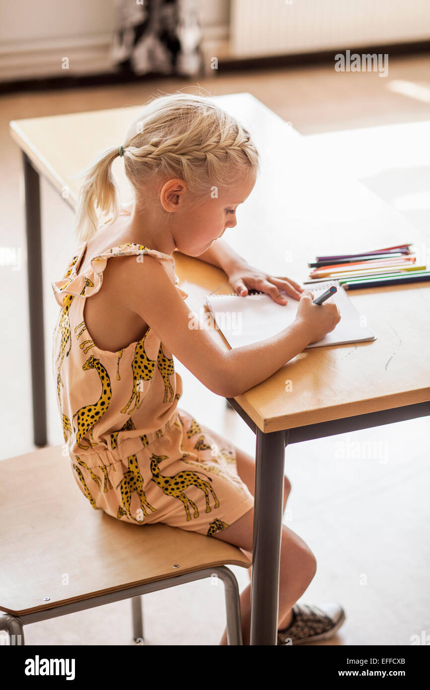 Side view of girl drawing at desk in classroom Stock Photo - Alamy