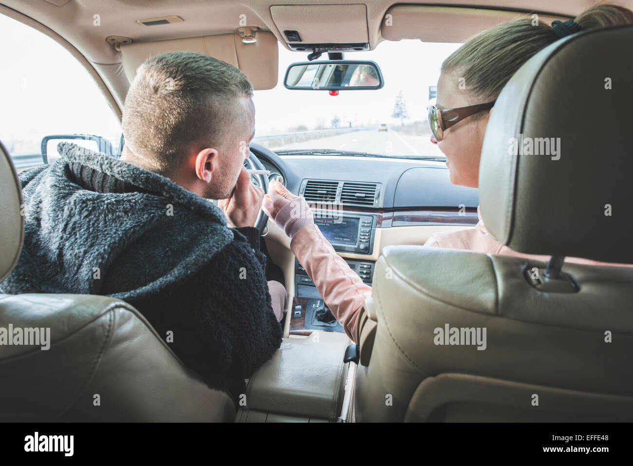 traveling with cigarettes Couple traveling in car with man smoking a cigarette Stock Photo