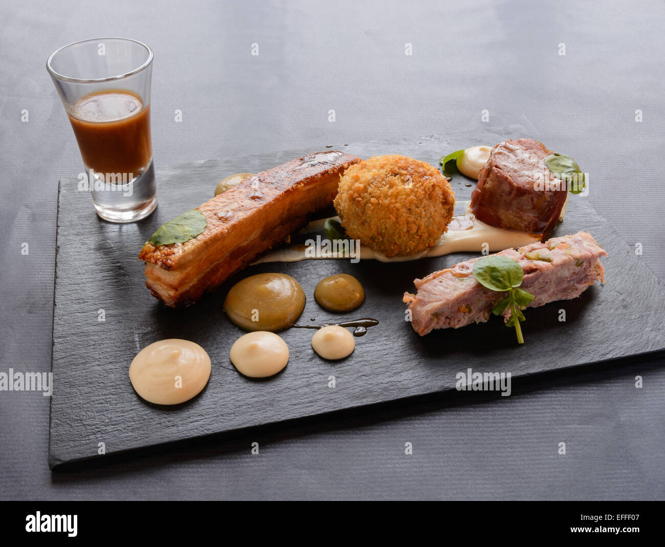 Pork 4 Ways: Sous vide (vacuum cooked) pork loin wrapped in Parma ham, ham hock terrine, pickled vegetables, crisp cider-braised Stock Photo