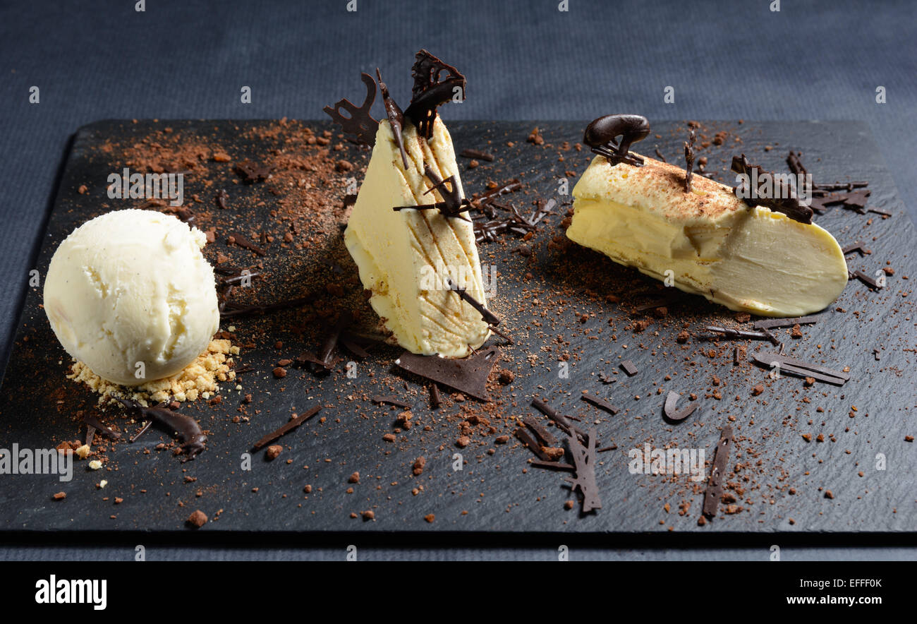 White chocolate and vanilla parfait with chocolate crumble on a black slate plate Stock Photo