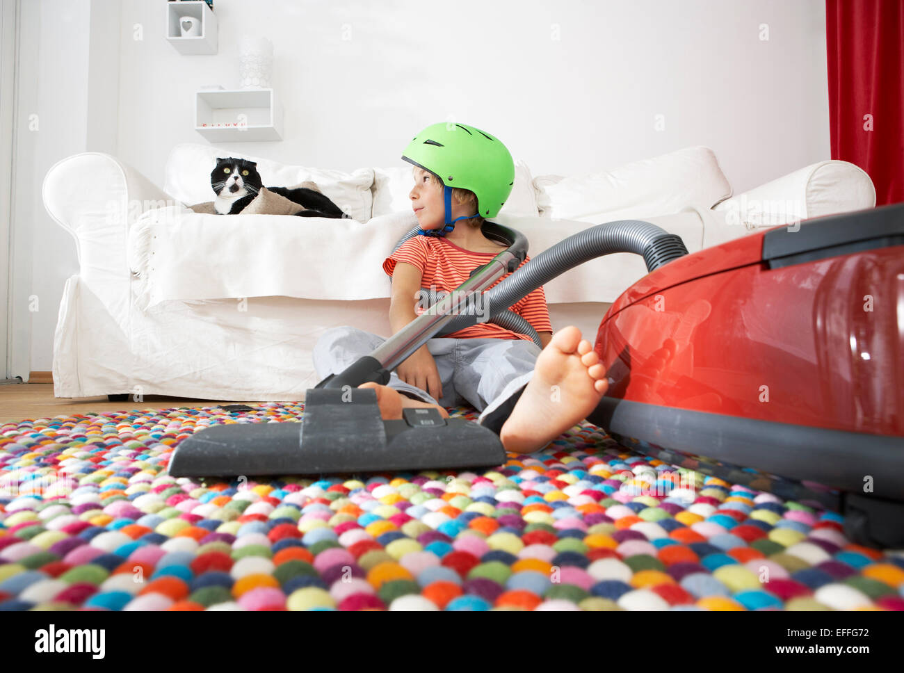 Boy in living room with cat and vacuum cleaner Stock Photo - Alamy