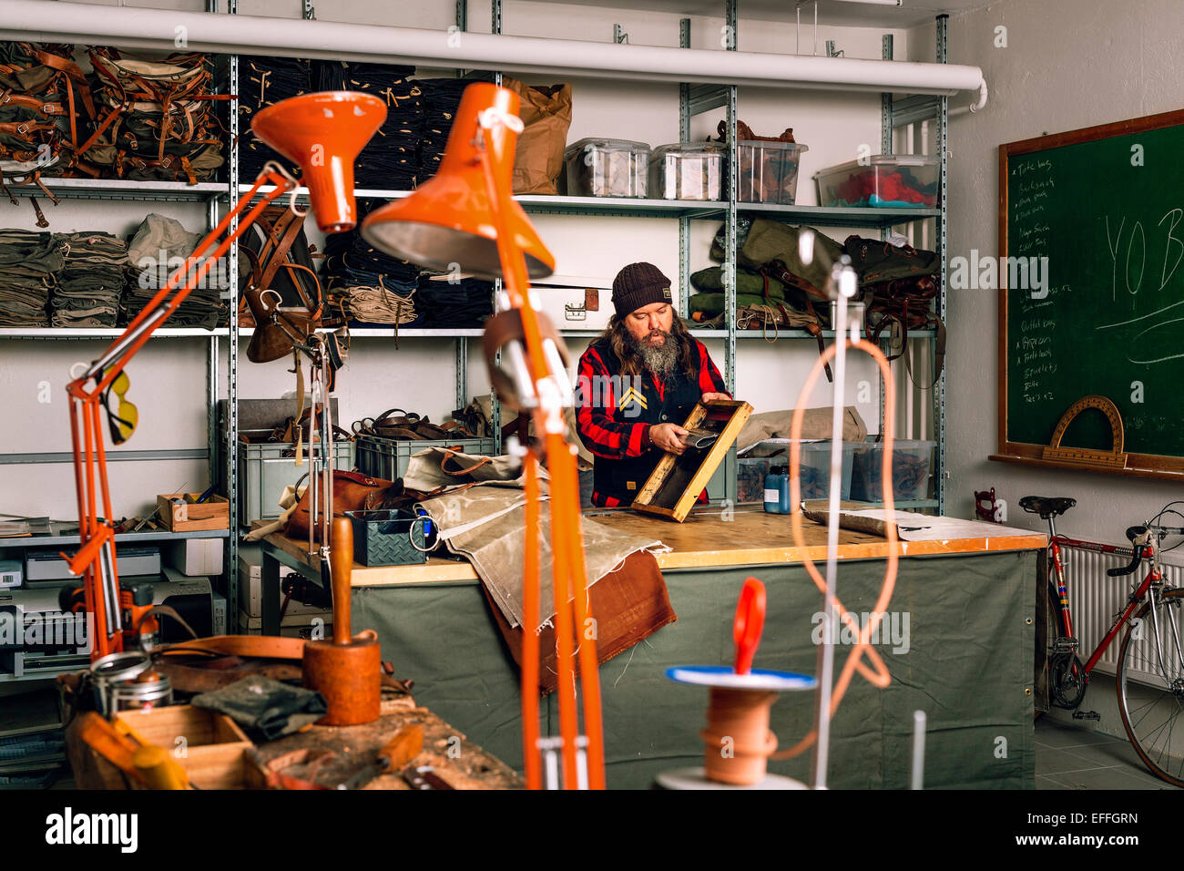 Male worker using squeegee to pull ink across stencil on screen at