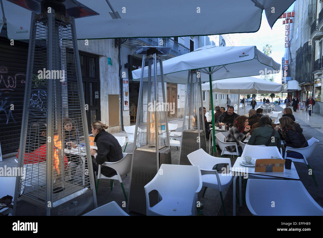 Customers at a street cafe in winter Valencia with patio flame heaters Stock Photo