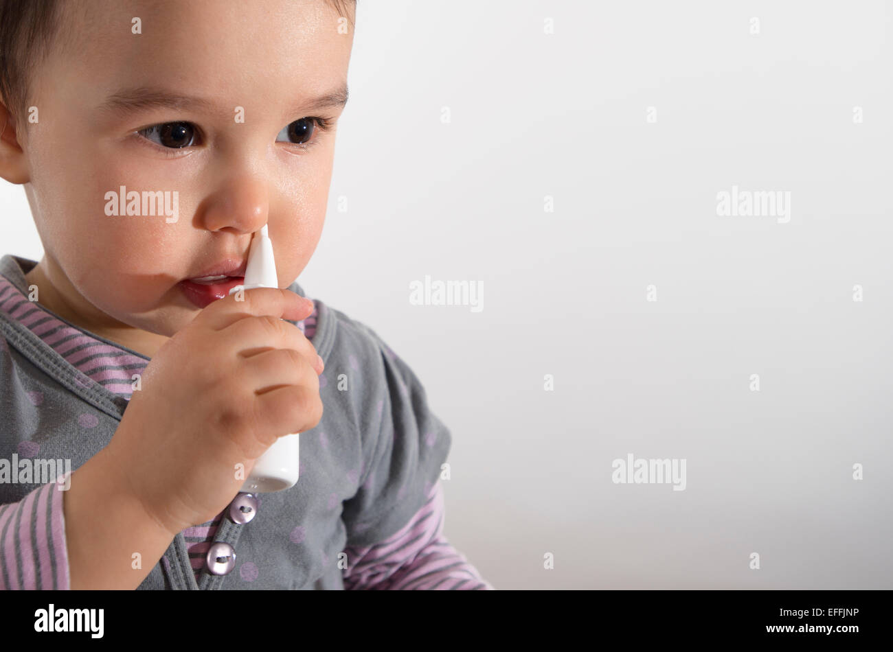 little girl using nasal spray - white background Stock Photo
