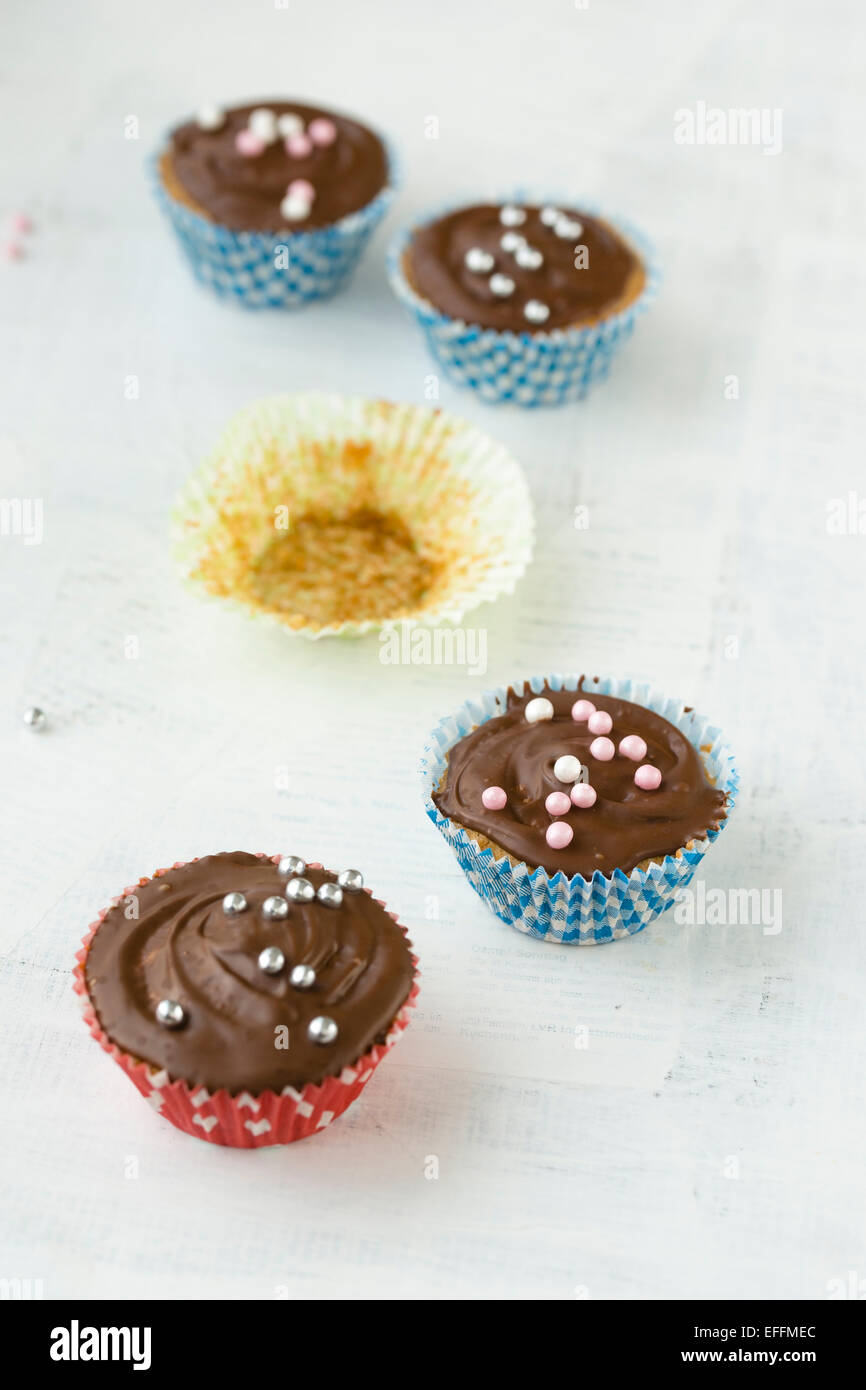 Four cupcakes with chocolate and sugar pearls and an empty paper cup Stock Photo