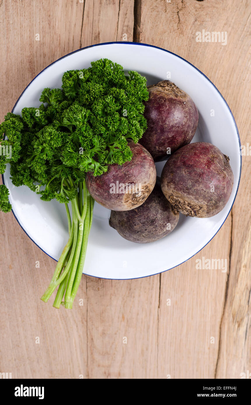 Bowl of frizzy parsley and beetroots on wood Stock Photo
