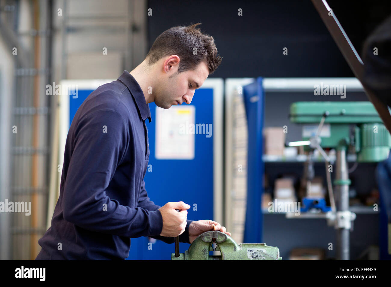 Young Technician Working At A Bench Vice In An Industrial Hall