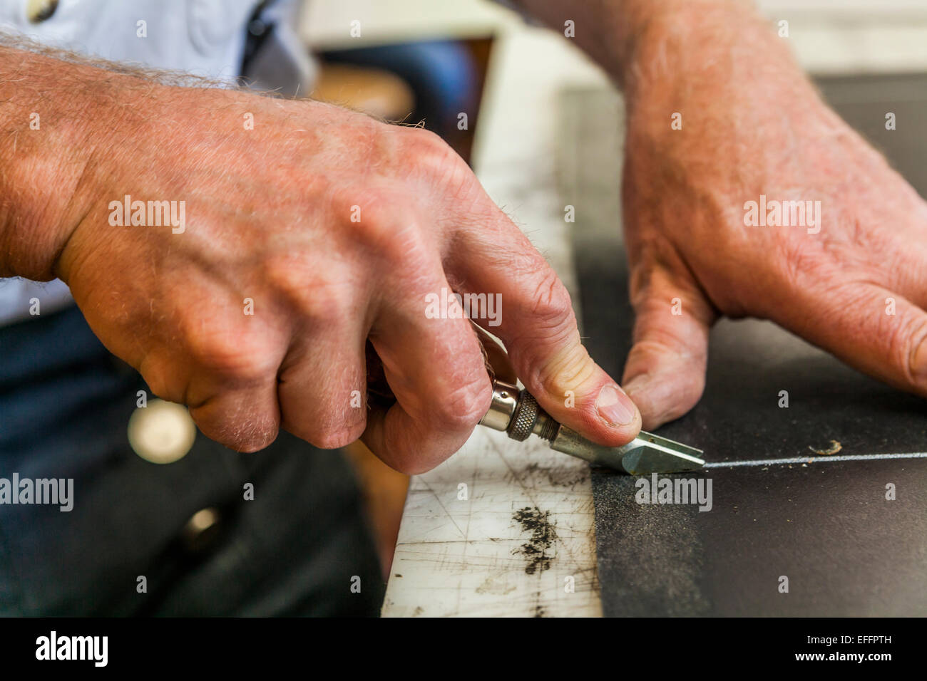 Saddler cutting leather with groove cutter Stock Photo