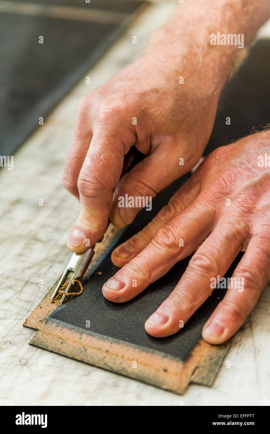 Saddler preparing leather with groove-cutter Stock Photo