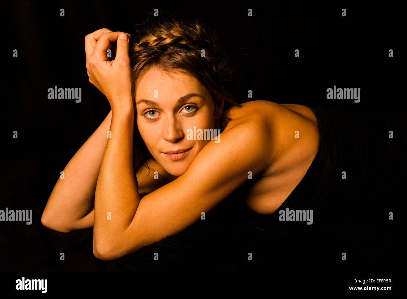 Portrait of smiling woman wearing black corsage in front of black background Stock Photo