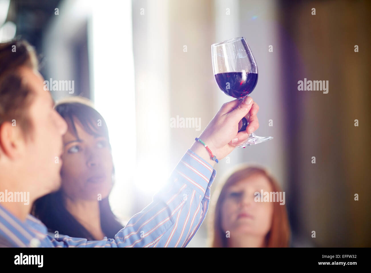 Man and two women examining red wine Stock Photo
