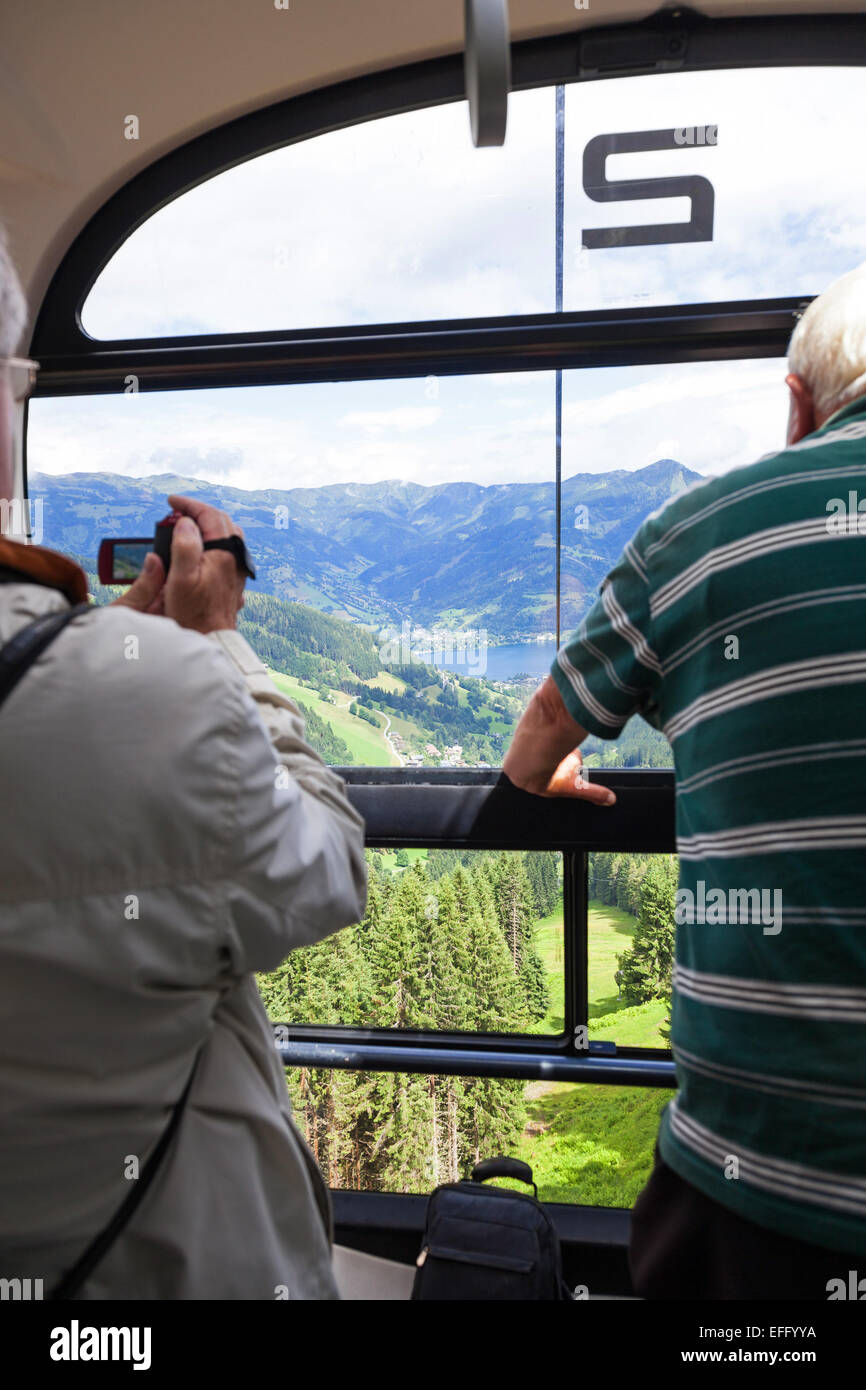 Two people, one taking a video, on the  Schmitten cable car ski lift at Schmittenhöhe Zell am See Austria in summer Stock Photo