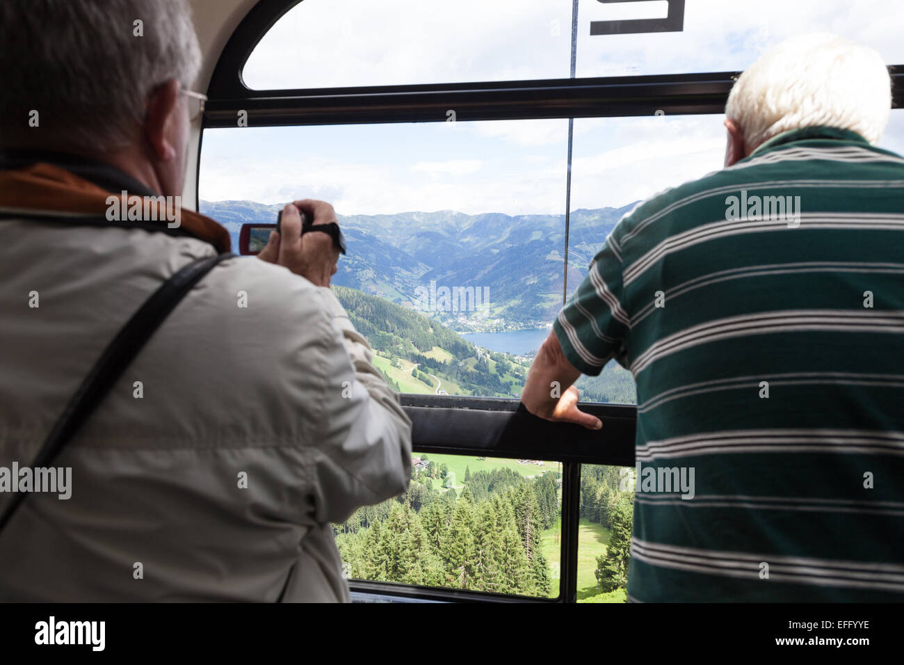 Two people, one taking a video, on the  Schmitten cable car ski lift at Schmittenhöhe Zell am See Austria in summer Stock Photo