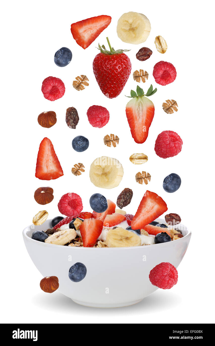 Falling ingredients of fruit muesli for breakfast in bowl with fruits like raspberry, blueberries, banana and strawberry Stock Photo