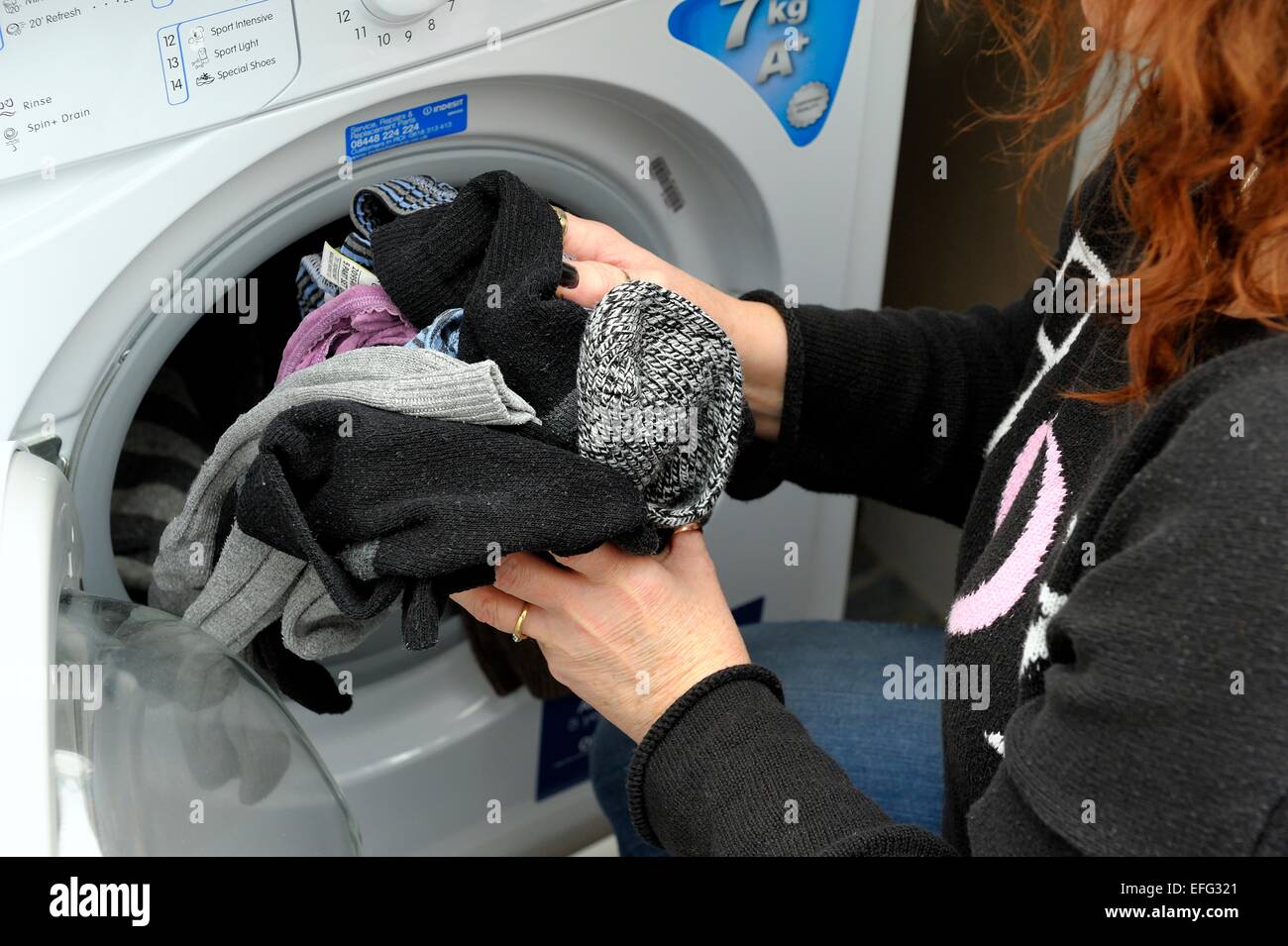 A woman removing washing from a dryer Stock Photo