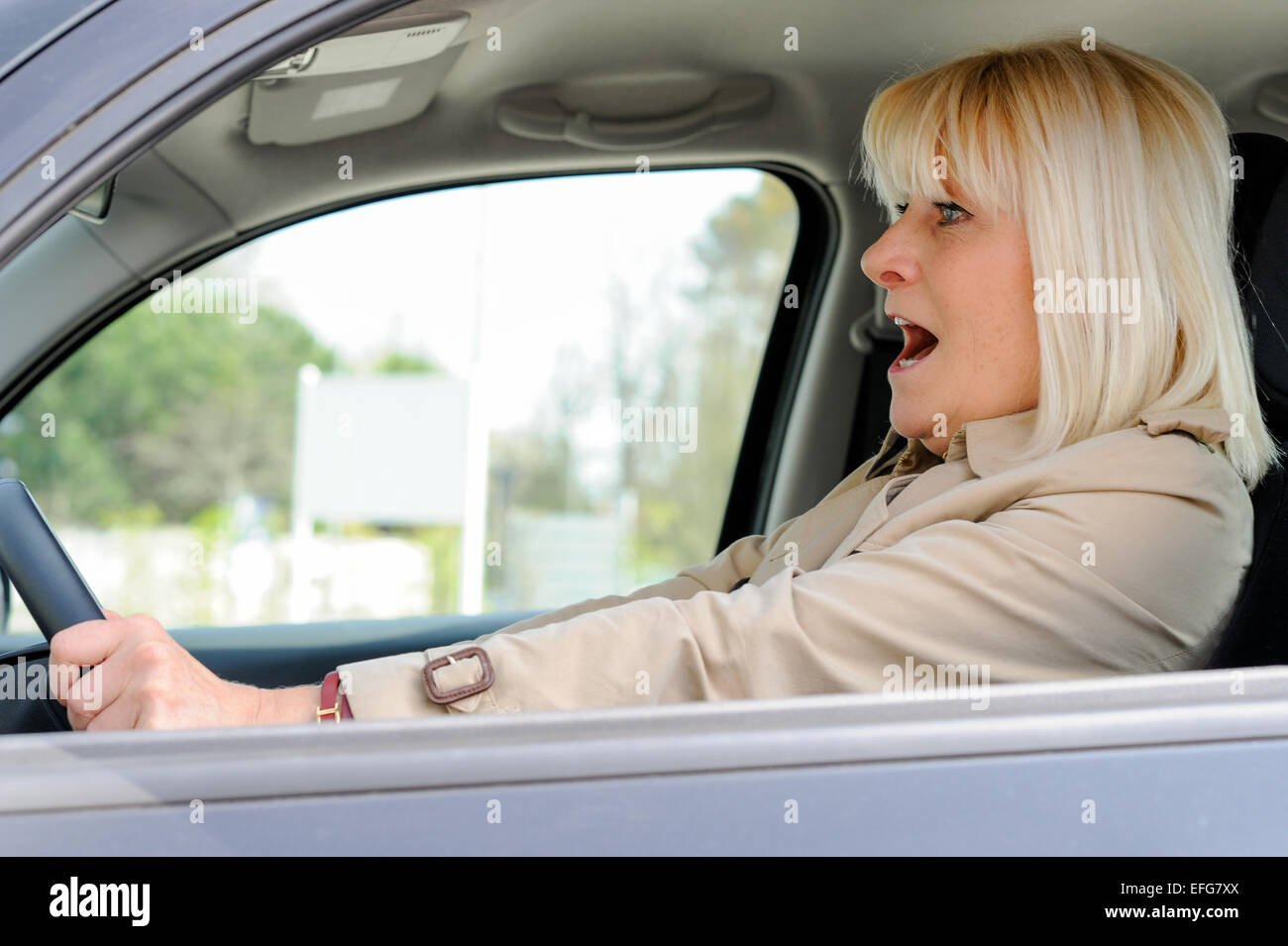 A senior woman frightened at the wheel of her car. Stock Photo