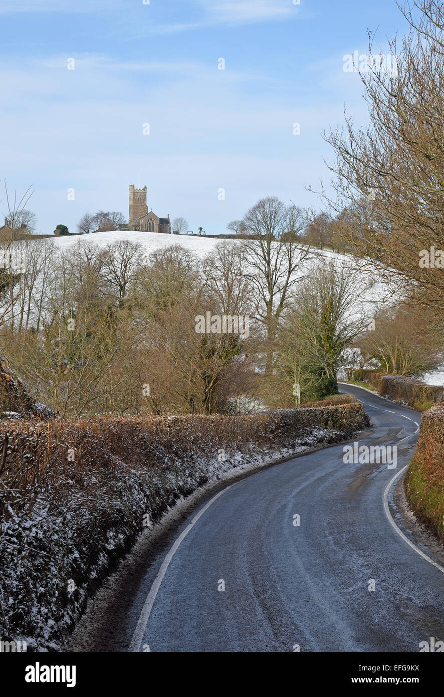 Road approaching Moretonhampstead, Dartmoor National Park in winter. The parish church of St Andrew can be seen on the hill. Stock Photo