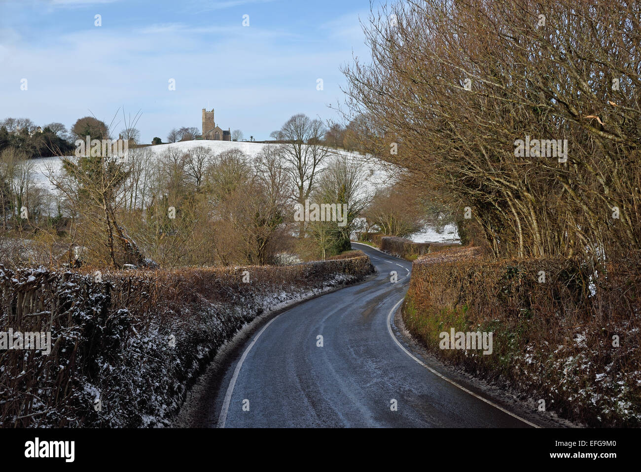 Road approaching Moretonhampstead, Dartmoor National Park in winter. The parish church of St Andrew can be seen on the hill. Stock Photo