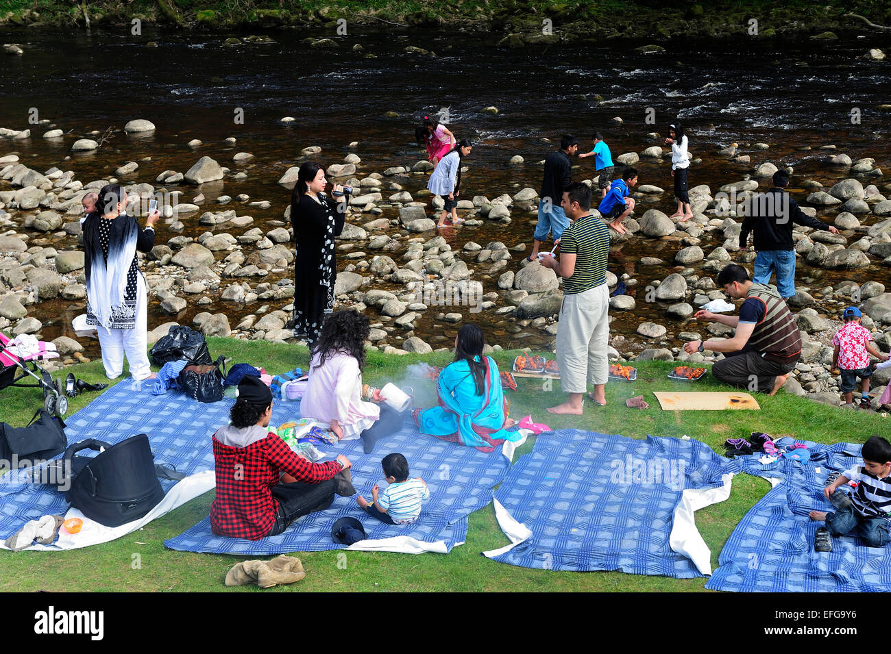 Families having a picnic on the River Wharfe, in the grounds of Bolton Abbey, Skipton West