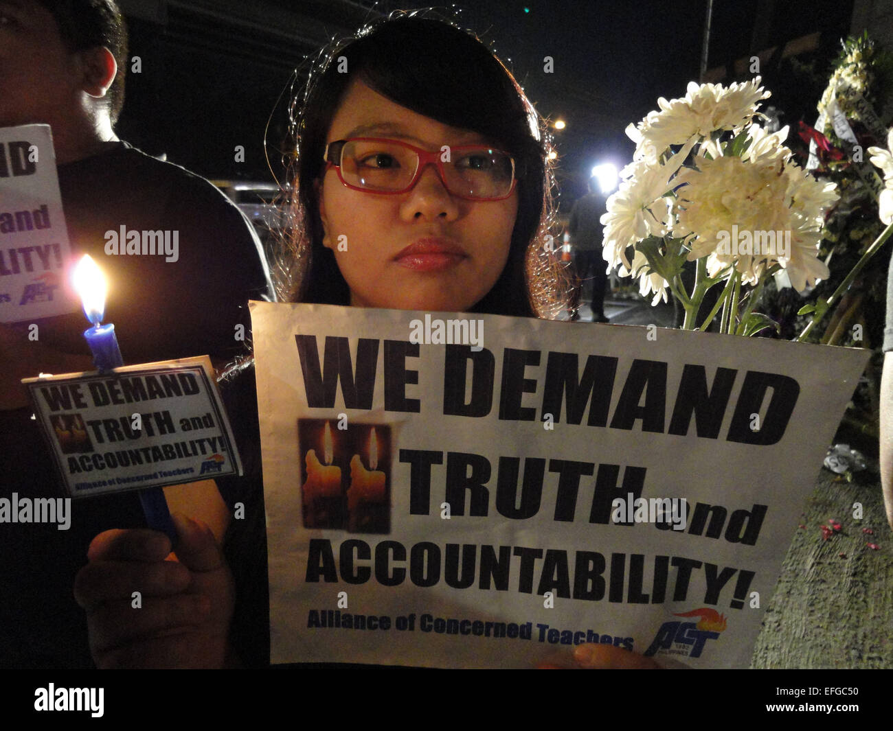 Quezon City, Philippines. 3rd Feb, 2015. An activist carries a candle, a flower, and a placard outside the Philippine National Police headquarters. A mass was celebrated outside the Philippine National Police headquarters as they called for truth and accountability for the casualties of the botched anti-terror operation in Mamasapano, Maguindanao provionce last January 25, including 44 police commandos, as well as several civilians. Credit:  Richard James Mendoza/Pacific Press/Alamy Live News Stock Photo