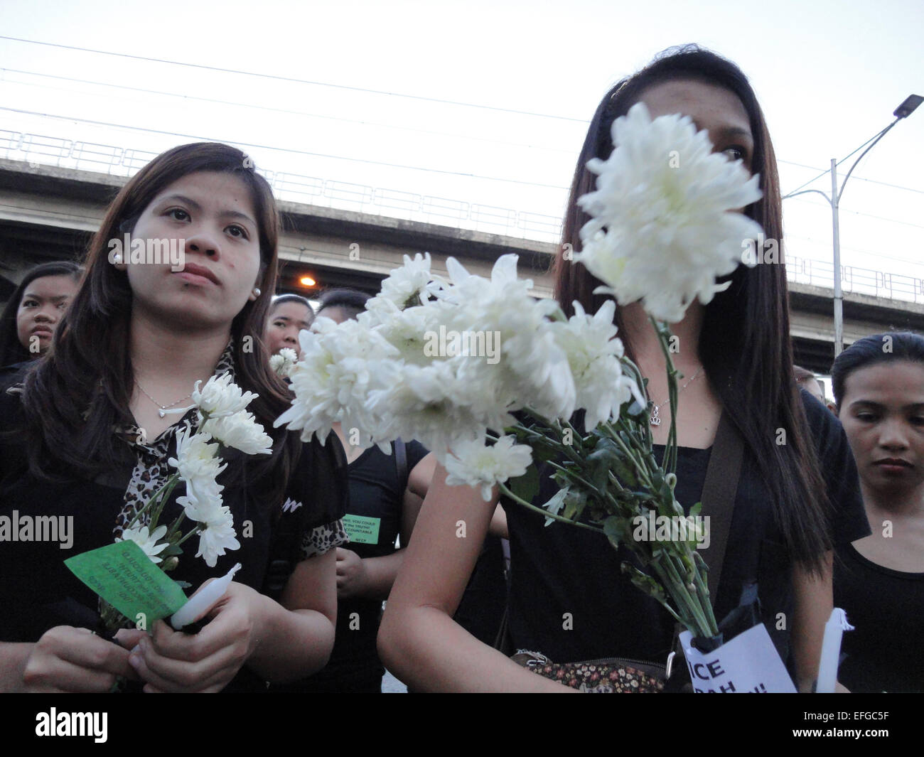 Quezon City, Philippines. 3rd Feb, 2015. Women dressed in black hold flowers tied with messages calling for justice outside the Philippine National Police headquarters. A mass was celebrated outside the Philippine National Police headquarters as they called for truth and accountability for the casualties of the botched anti-terror operation in Mamasapano, Maguindanao provionce last January 25, including 44 police commandos, as well as several civilians. Credit:  Richard James Mendoza/Pacific Press/Alamy Live News Stock Photo