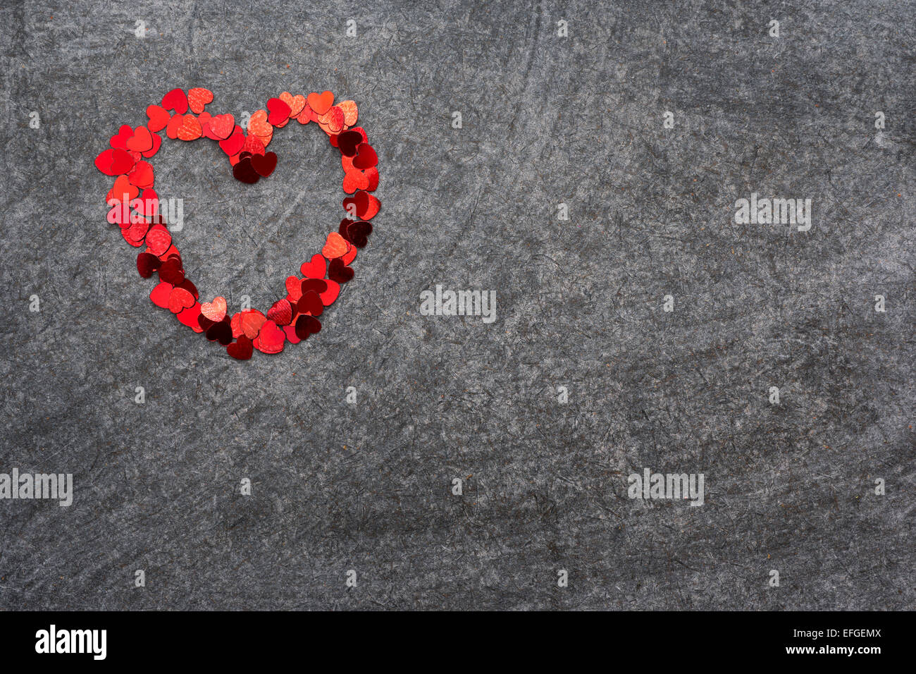 small red  heart figure made from many confetti pieces on blank blackboard Stock Photo