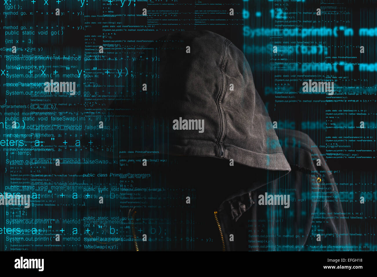 Faceless hooded anonymous computer hacker with programming code from monitor Stock Photo